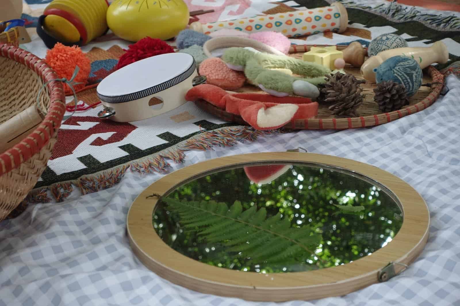 Outdoor play setup with toys, mirror, and natural elements for children.