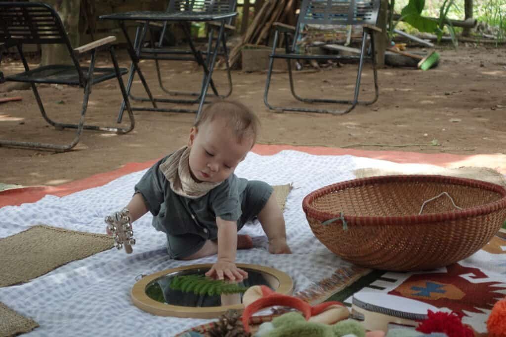Baby exploring nature with toys and natural surroundings.